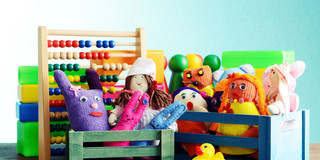 Spielerisches Lernen Bunte Handpuppen und Quietscheentchen vor einem Rechenschieber und Bauklötzen.